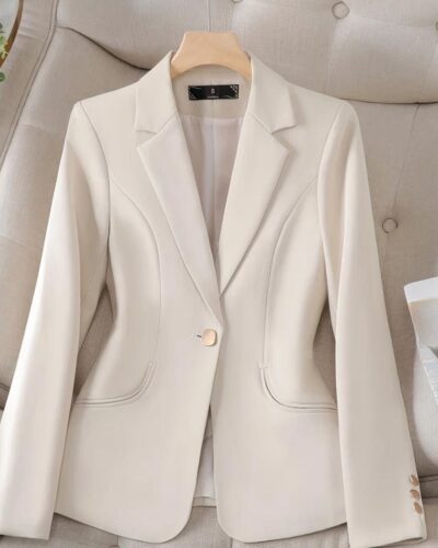 Blazer beige avec un bouton posé sur un canapé beige