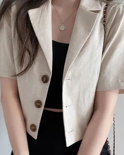 Blazer beige court et manches courtes porté par une femme brune