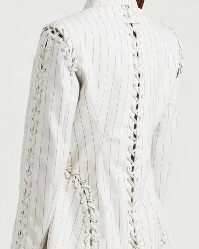 Femme portant un blazer blanc sur fond blanc.