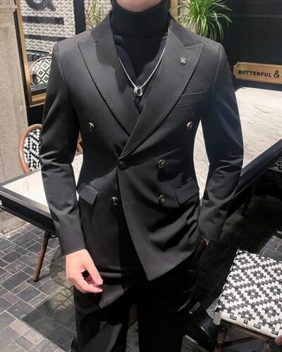 Homme portant un blazer croisé et se trouvant devant une table.