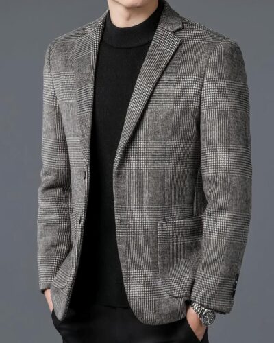 Homme portant un blazer gris et un haut noir sur fond gris.