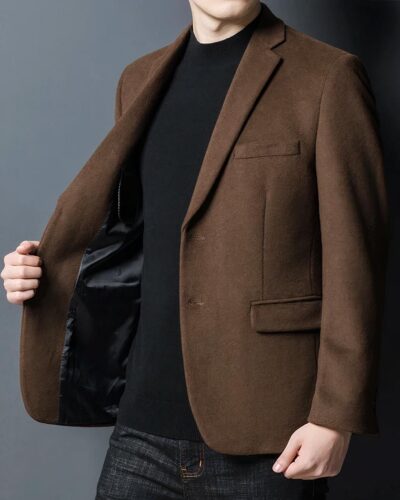 Homme portant un blazer marron sur fond gris.