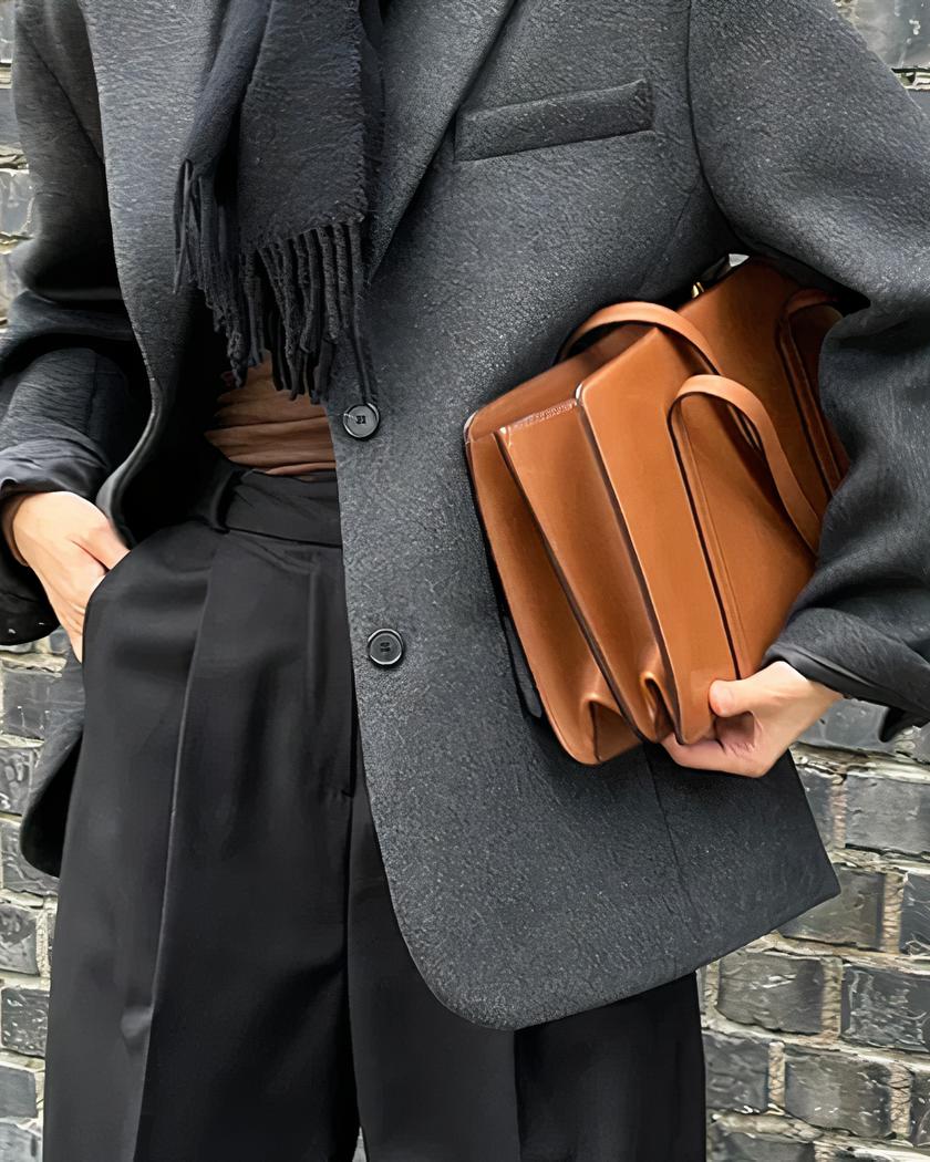 Blazer gris d'hiver pour femme Femme portant un blazer gris et tenant un sac marron.