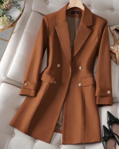 Blazer long de couleur marron posé sur un canapé blanc.