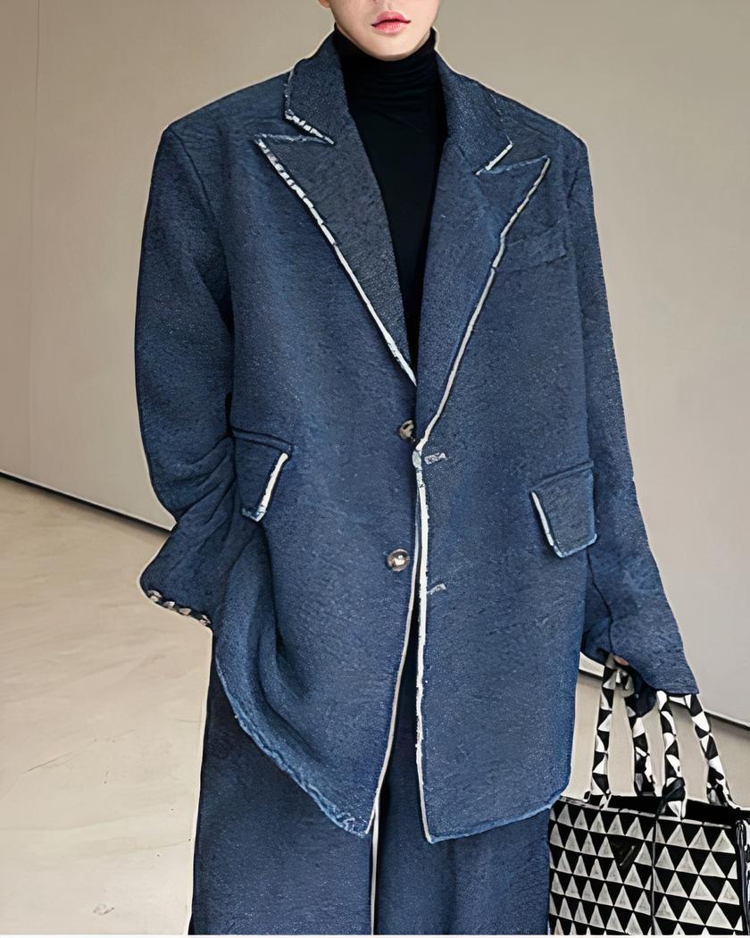 Blazer long denim pour homme Homme portant un blazer bleu et tenant un sac à main.