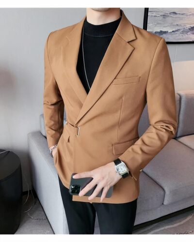 Homme portant un blazer croisé orange et tenant un téléphone dans sa main.