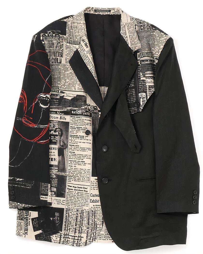 Blazer oversize homme imprimé journal Photo d'un blazer homme oversize noir imprimé journal avec poches devant sans rabat, trois boutons et martingale sur le revers gauche à attacher ou non sur un petit bouton du même côté