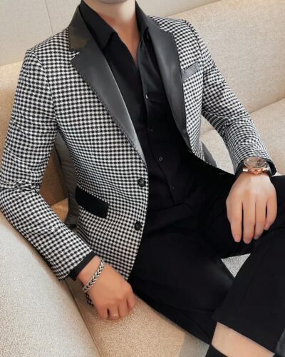Un homme en blazer pied de poule noir et blanc est assis sur un canapé beige