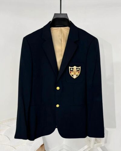 Blazer bleu avec un écuson et 2 bouton dorés suspendu par un ceintre