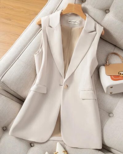 Blazer sans manche long beige posé sur un canapé beige