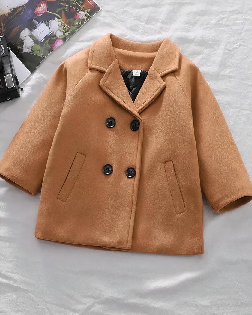 On voit un manteau blazer col croisé couleur marron camel, très chic, court.