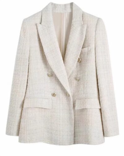 On voit un blazer en tweed blanc avec des boutons dorés, court et très élégant.