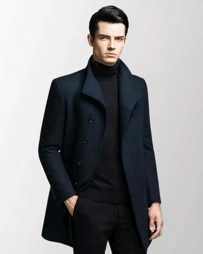 On voit un homme brun qui porte un manteau blazer noir très élégant et cintré.