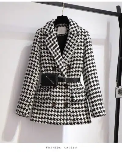 Blazer type manteau pied-de-poule en lainage pour femme sur un cintre sur un portant noir.