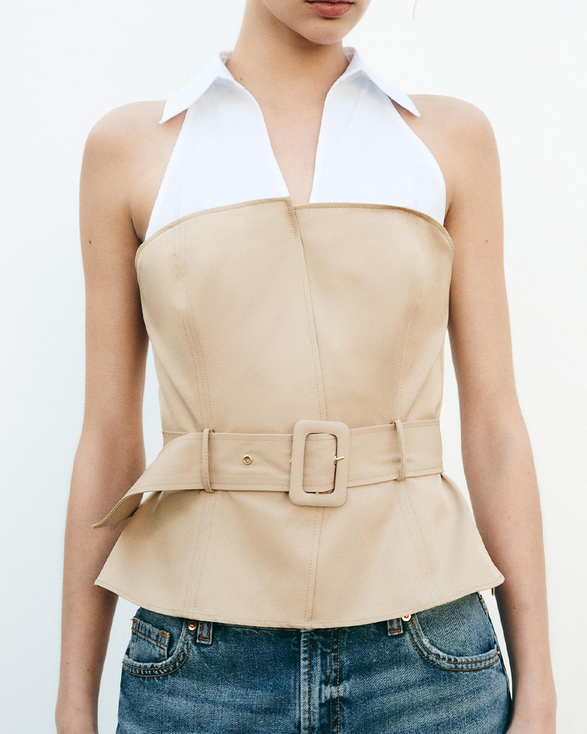 IMG_04_29_gilet_blazer_bicolore_col_ouvert_main Femme caucasienne portant un gilet blazer bicolore à col ouvert beige et blanc, sur un fond blanc uni