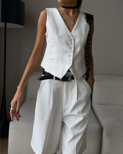 Femme à la peau mate portant un ensemble blazer gilet short long pour femme blanc dans une pièce claire obscure